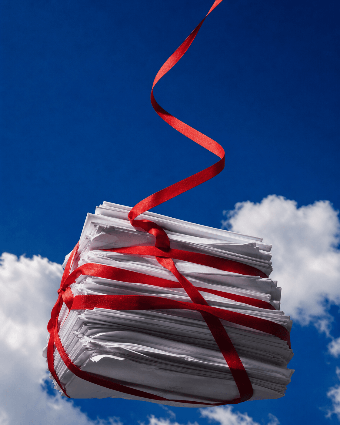 A stack of loose contract pages bound in scarlet ribbon against a blue sky